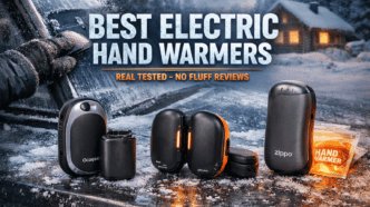 Alt text: Compact electric hand warmers displayed on snowy outdoor table with winter cabin in background.